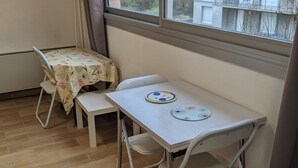 A small room with a window, a table, two chairs, and a tablecloth. - Quiet apartment - furnished (Rouen)