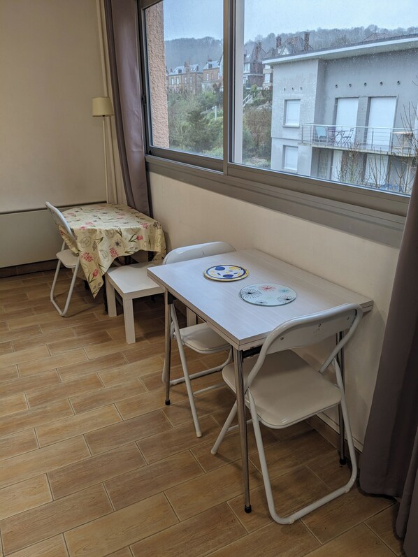 A small room with a window, a table, two chairs, and a tablecloth.