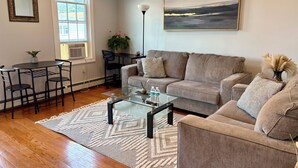 A living room with a sofa, coffee table, and a painting on the wall.
