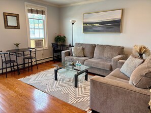A living room with a sofa, coffee table, and a painting on the wall.