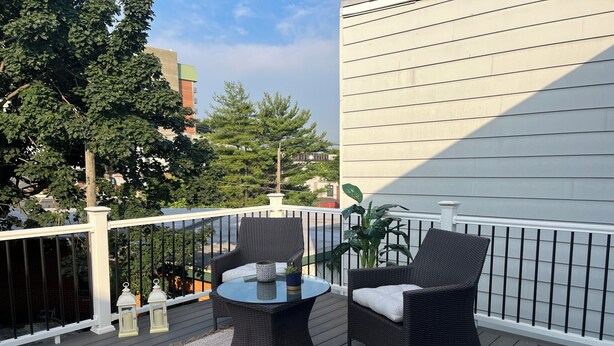 A balcony with two wicker chairs, a small round table, and a potted plant.
