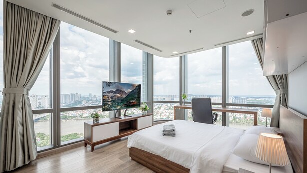 A modern hotel room with a large bed, a TV, and a city view. - Vinhomes Central Park Landmark 81-Apts (Ho Chi Minh City)