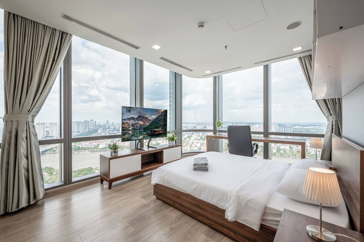 Ein modernes Hotelzimmer mit einem großen Bett, einem Fernseher und Blick auf die Stadt.