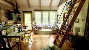 Un interior rústico con una mesa de comedor de madera, un sofá y una escalera.
