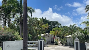 L’entrée d’un hôtel, avec une enseigne indiquant « Hôtel Residence La Métisse » et une allée d’accès fermée par un portail.
