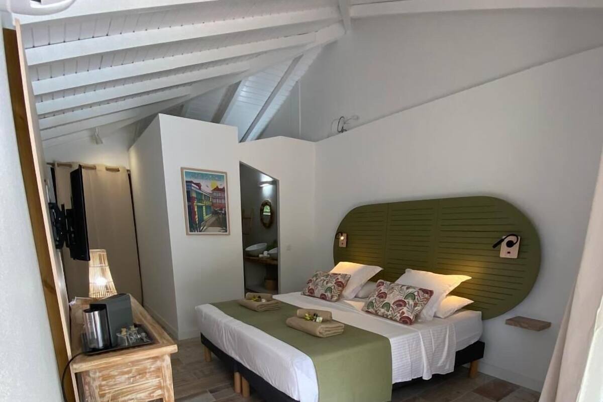 Ein Schlafzimmer mit einem Bett, einem Nachttisch, einer Lampe und einem Blumentopf.