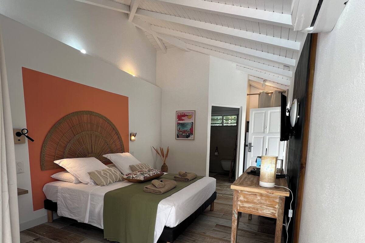 Ein Schlafzimmer mit einem Bett, einem Nachttisch, einem an der Wand montierten Fernseher und einem Poster.