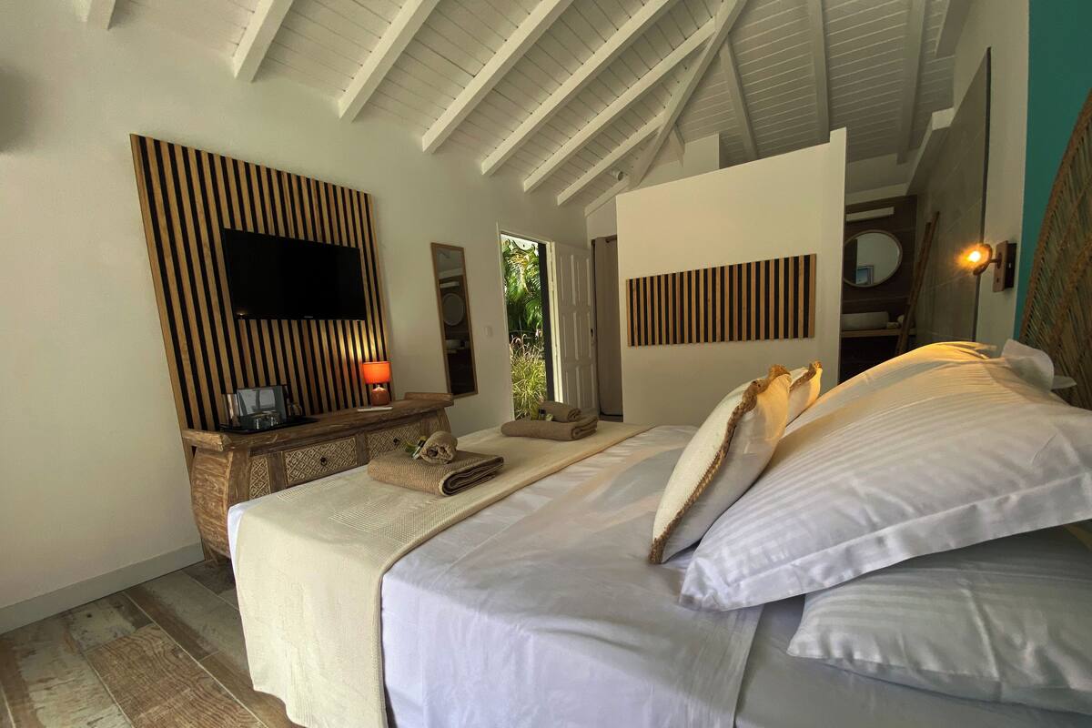 Ein Schlafzimmer mit einem Bett, einem Nachttisch mit Lampe, einem Spiegel und einer Wand aus Holzpaneelen.