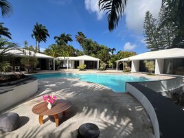A pool area with a modern design, including a circular seating area with a table and a vase of flowers.