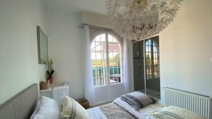 A bedroom with a large bed, a window with a view, a ceiling light fixture, and a radiator. - Spacious house with garden and pool (Arcachon)