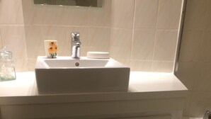 Ein Badezimmer mit weißem Waschbecken, Spiegel und Schränken.