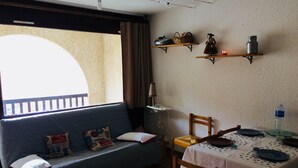Ein gemütliches Zimmer mit einer Couch, einem Esstisch für zwei Personen und Regalen darüber.