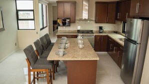A modern kitchen with a central island, wooden chairs, a stainless steel refrigerator, and a gas stove. - Apartment for 8 with terrace and BBQ in the city center (Arandas)