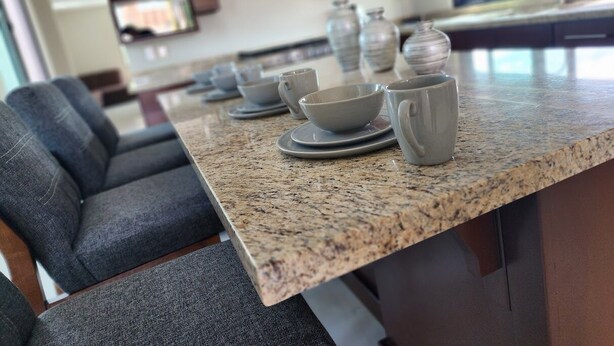 A kitchen with granite countertops, a dining area with gray upholstered chairs, and a view of the living room. - Apartment for 8 with terrace and BBQ in the city center (Arandas)