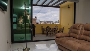 A living room with a brown sofa, a glass door leading to a balcony with a table and chairs, and a view of buildings. - Apartment for 8 with terrace and BBQ in the city center (Arandas)