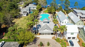 A residential area with a large swimming pool surrounded by houses, a lake in the background, and a well-maintained lawn. - Close to 2 Beach Accesses, Resort Pool, Bikes, Gulf View (Inlet Beach)