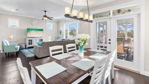A dining area with a wooden table, white chairs, and a vase of flowers. - Close to 2 Beach Accesses, Resort Pool, Bikes, Gulf View (Inlet Beach)