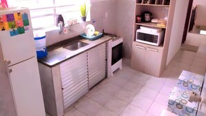 Une cuisine de taille réduite équipée d’un évier, d’un four à micro-ondes et d’un réfrigérateur.