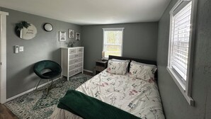 Ein Schlafzimmer mit Bett, Schminktisch, Stuhl, Fenster und Wanddekorationen.