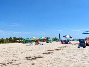 A beach with multiple colorful umbrellas and beach chairs. - Villa Pelican Point by swflorida-villas with gulf access  in SW Cape Coral (Cape Coral)