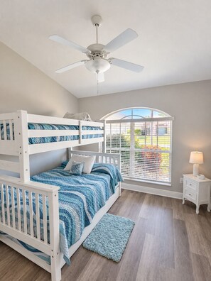 A bunk bed room with a ceiling fan, a window with blinds, and a bedside table with a lamp. - Villa Pelican Point by swflorida-villas with gulf access  in SW Cape Coral (Cape Coral)