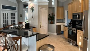 Una cocina moderna con una isla central, armarios de madera y electrodomésticos de acero inoxidable, además de un ventilador de techo.