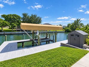 A dock with a covered seating area, a small shed, and a grassy area.
