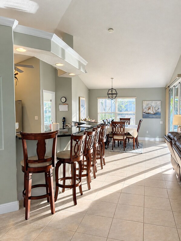 A spacious kitchen with a central island, bar stools, and a dining area with chairs.