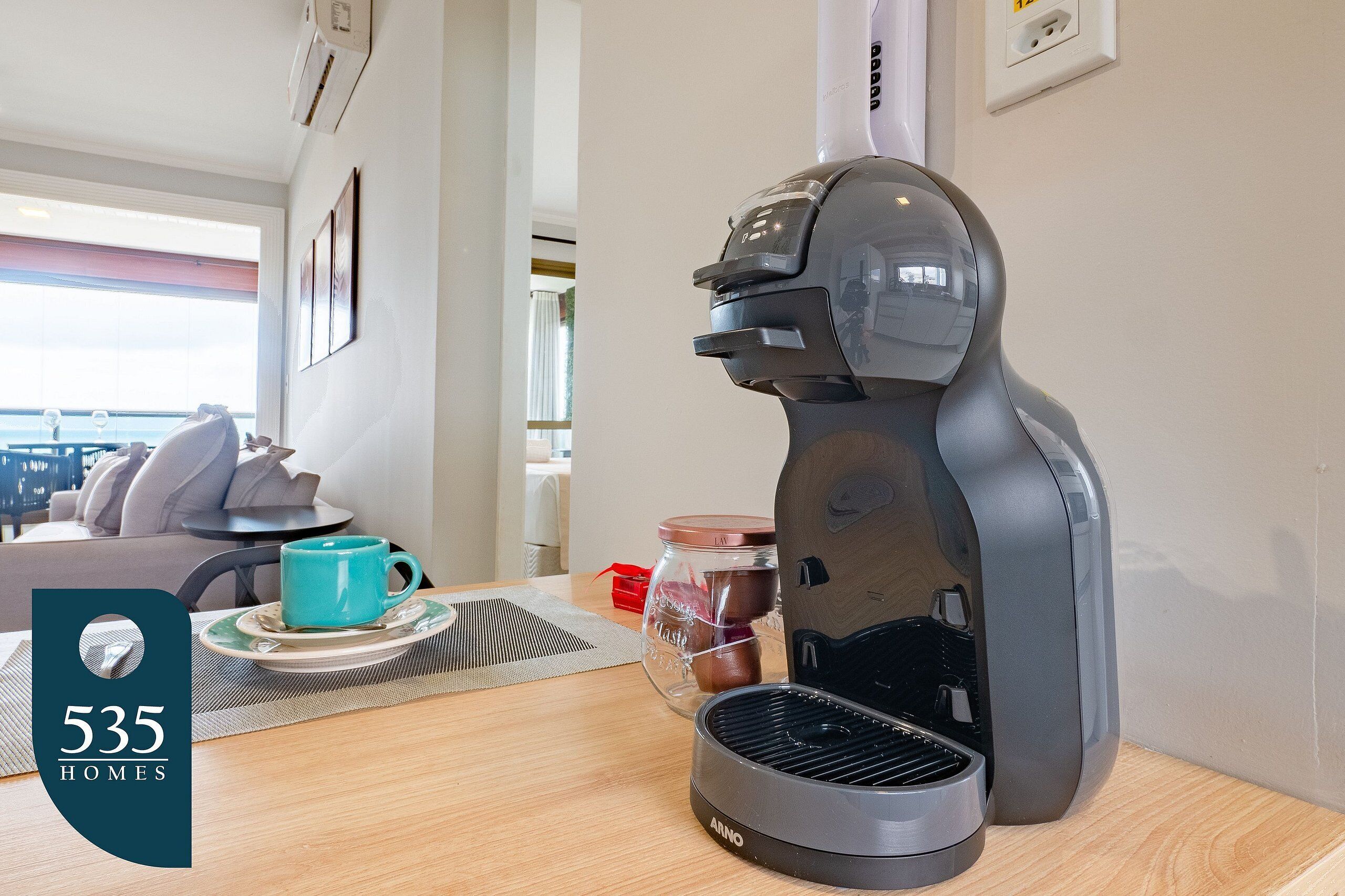 Ett modernt kök med en kaffebryggare, en mugg och ett glas med sylt på bänkskivan.