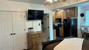 A bedroom with a bed, a dresser, a TV, and a ceiling fan.