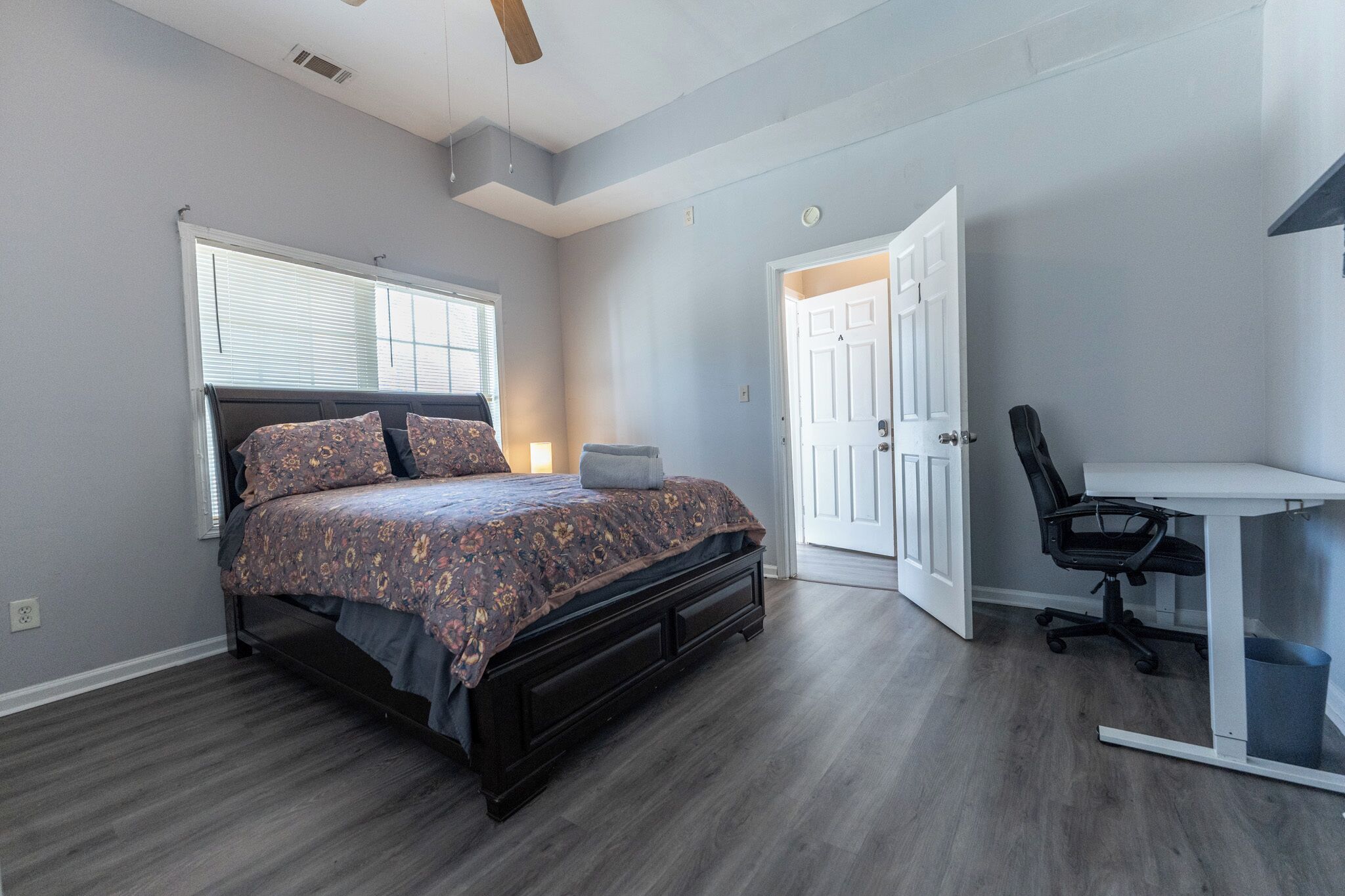 A bedroom with a bed, a desk, and a chair.