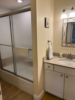 A bathroom with a glass shower enclosure, a sink with a mirror, and a towel rack. - 4-bedroom direct beachfront. Non-drive beach with pool in fabulous Daytona Beach (Ponce Inlet)