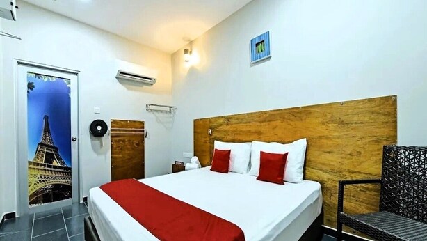 A hotel room with a bed, a chair, a nightstand, and a wall-mounted air conditioner. - RS Hotel Desa Cemerlang Johor Jaya (Johor Bahru)