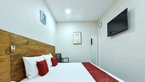 A hotel room with a wooden headboard, a bed with white and red bedding, a red throw blanket, a flat-screen TV mounted on the wall, and a framed inspirational quote on the wall. - RS Hotel Desa Cemerlang Johor Jaya (Johor Bahru)