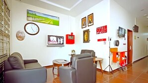 A modern hotel lobby with a sofa, armchairs, a small table, and a TV. - RS Hotel Desa Cemerlang Johor Jaya (Johor Bahru)