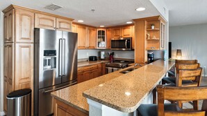 Eine moderne Küche mit Holzschränken, Edelstahlgeräten und einer Arbeitsplatte aus Granit.