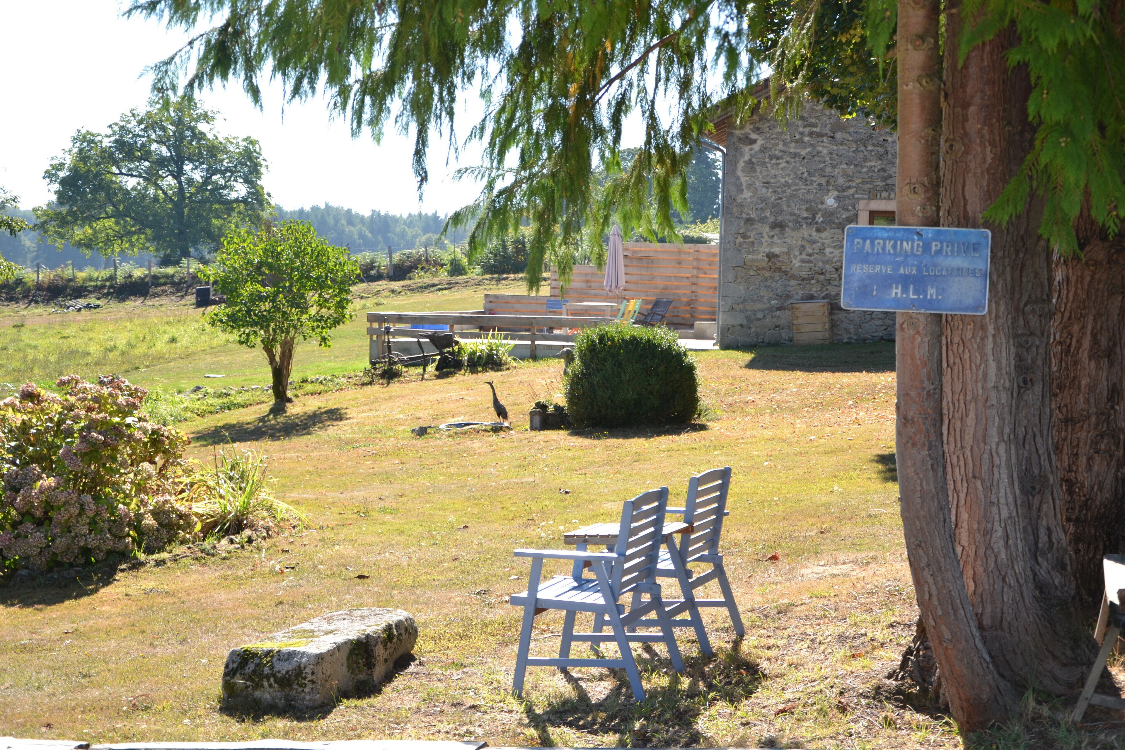 Un espace extérieur paisible, avec un banc en bois, un mur de pierre et un panneau indiquant un emplacement de stationnement.