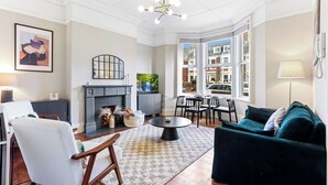 Una sala de estar con chimenea, un comedor y ventanas amplias con vistas a la ciudad.