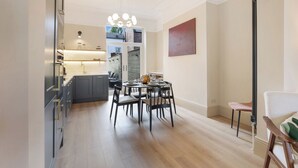 Una cocina moderna con armarios oscuros y una zona de comedor con una mesa redonda y sillas.