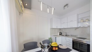 A modern kitchen with white cabinets, a built-in oven, and a dining area with a table set for two.