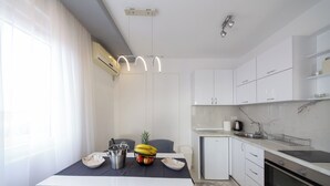 A modern kitchen with white cabinets, a marble countertop, and a dining area with a table set for two.