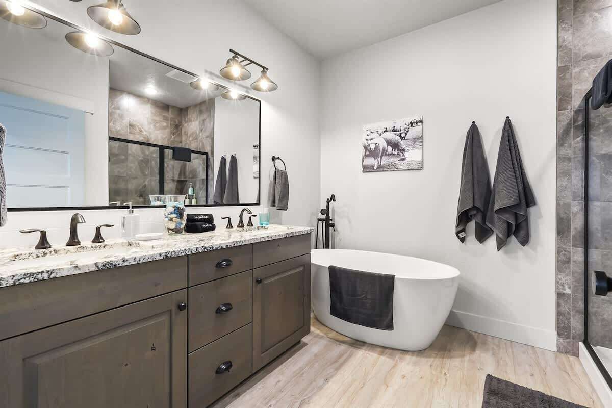 Une salle de bain moderne avec une baignoire sur pieds, un grand miroir et un meuble-lavabo doté d’un plan de travail en marbre.