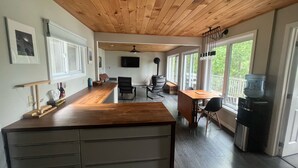 Un'ampia cucina con soffitto in legno, un'area pranzo con tavolo e sedie, e un'ampia finestra che offre vista sull'esterno.