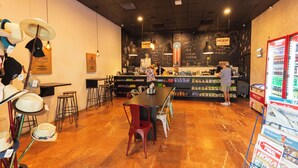 L’intérieur d’un restaurant, avec un bar, des tables et un présentoir à chapeaux.