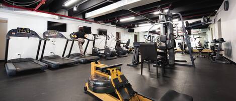 A gym with treadmills, a rowing machine, and various weightlifting equipment.