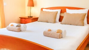 A neatly made bed with two rolled towels and seashells, a wooden headboard, and a nightstand with a lamp. - Modern villa with BBQ and heatable pool (Albufeira)