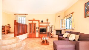 A living room with a purple sofa, a TV, and a fireplace. There is a staircase leading to another room. - Modern villa with BBQ and heatable pool (Albufeira)