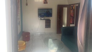 A living room with a television mounted on the wall, a glass coffee table, and a sofa. - Furnished and air-conditioned 2-bedroom apartment living room (Dakar)