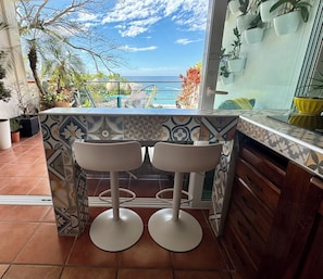 Enjoy ocean views from this kitchen with a sink, countertop, and bar stools.