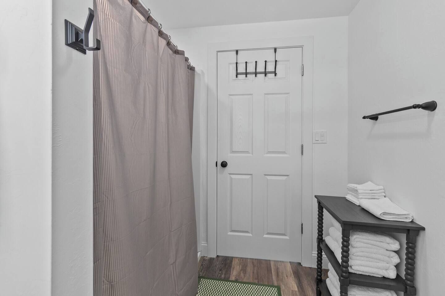 A hallway with a white door, a towel rack, and a small shelf with folded towels.